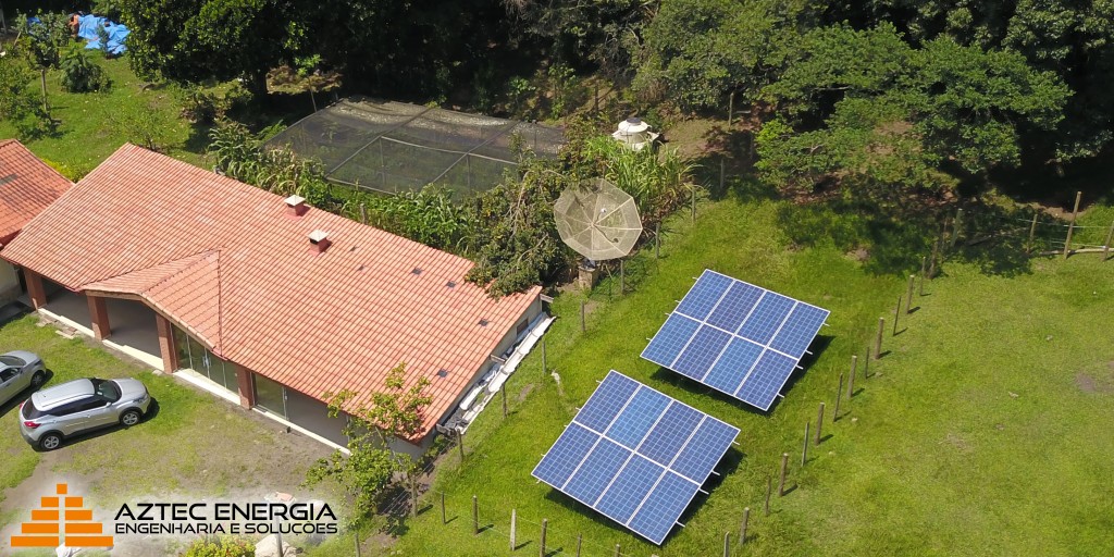 Instalação da Aztec de painéis fotovoltaicos ao lado de uma casa com estufa.